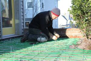 A Concord Carpenter, Rob Robillard, installas a WarmlyYours snow melting system in a wheelchair ramp for Massachusetts homeowner Rob Butts.
